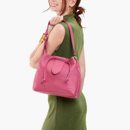 Wild Rose*Large | Model holding symmetrical leather bag with leather drawstring closure and adjustable shoulder strap