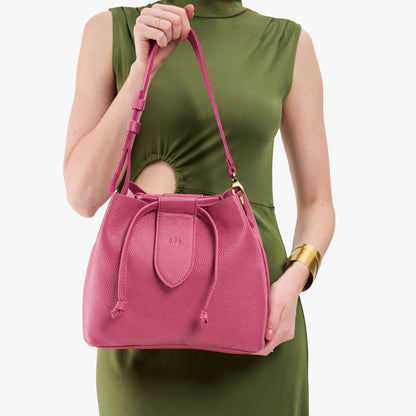 Wild Rose*Large | Model holding symmetrical leather bag with leather drawstring closure and adjustable shoulder strap