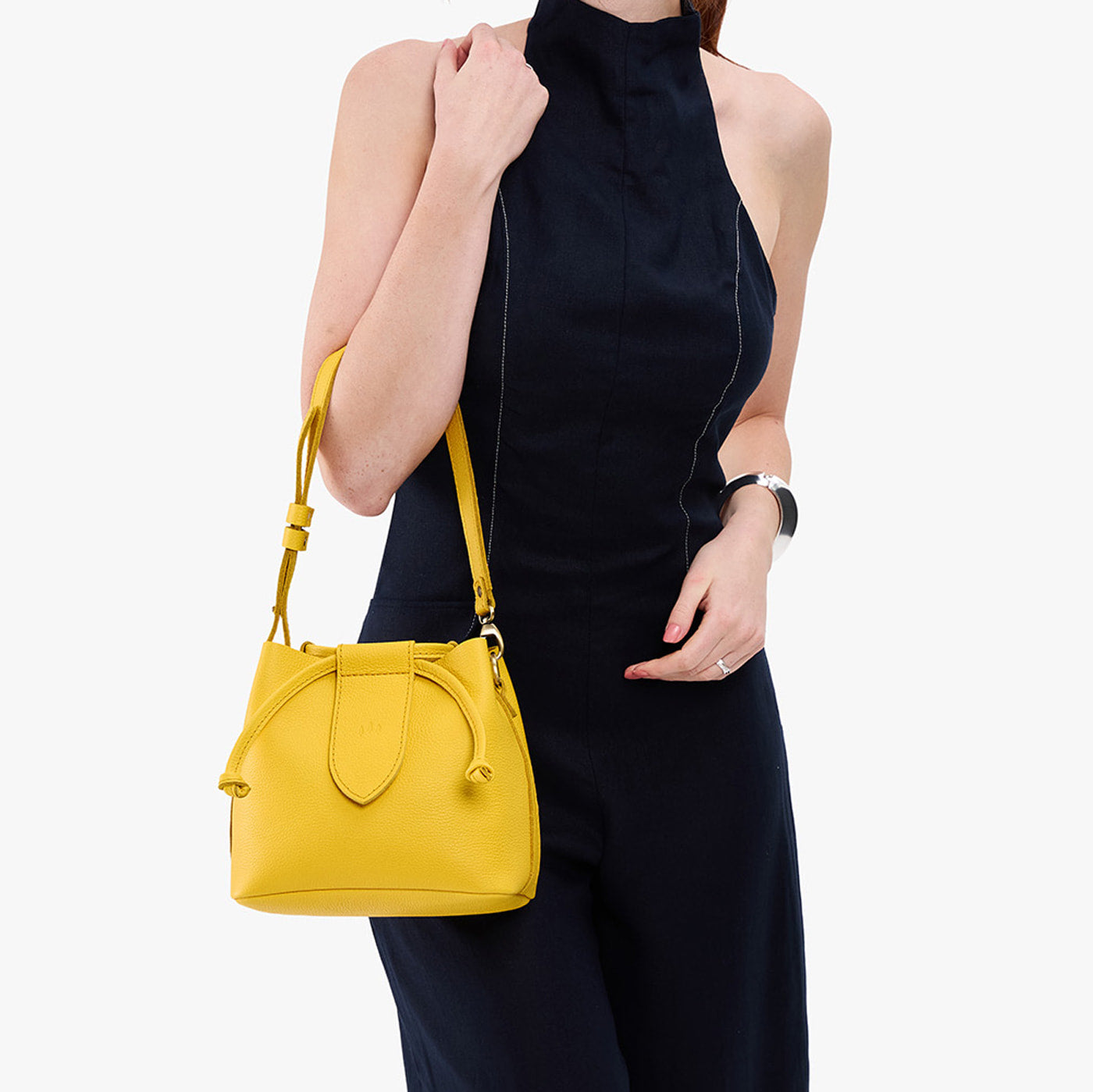 Canary*Small | Model holding symmetrical leather bag with leather drawstring closure and adjustable shoulder strap