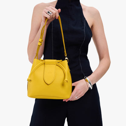 Canary*Small | Model holding symmetrical leather bag with leather drawstring closure and adjustable shoulder strap