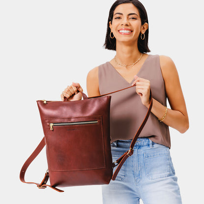 All Color: Cognac | Model holding rectangular slim leather laptop backpack