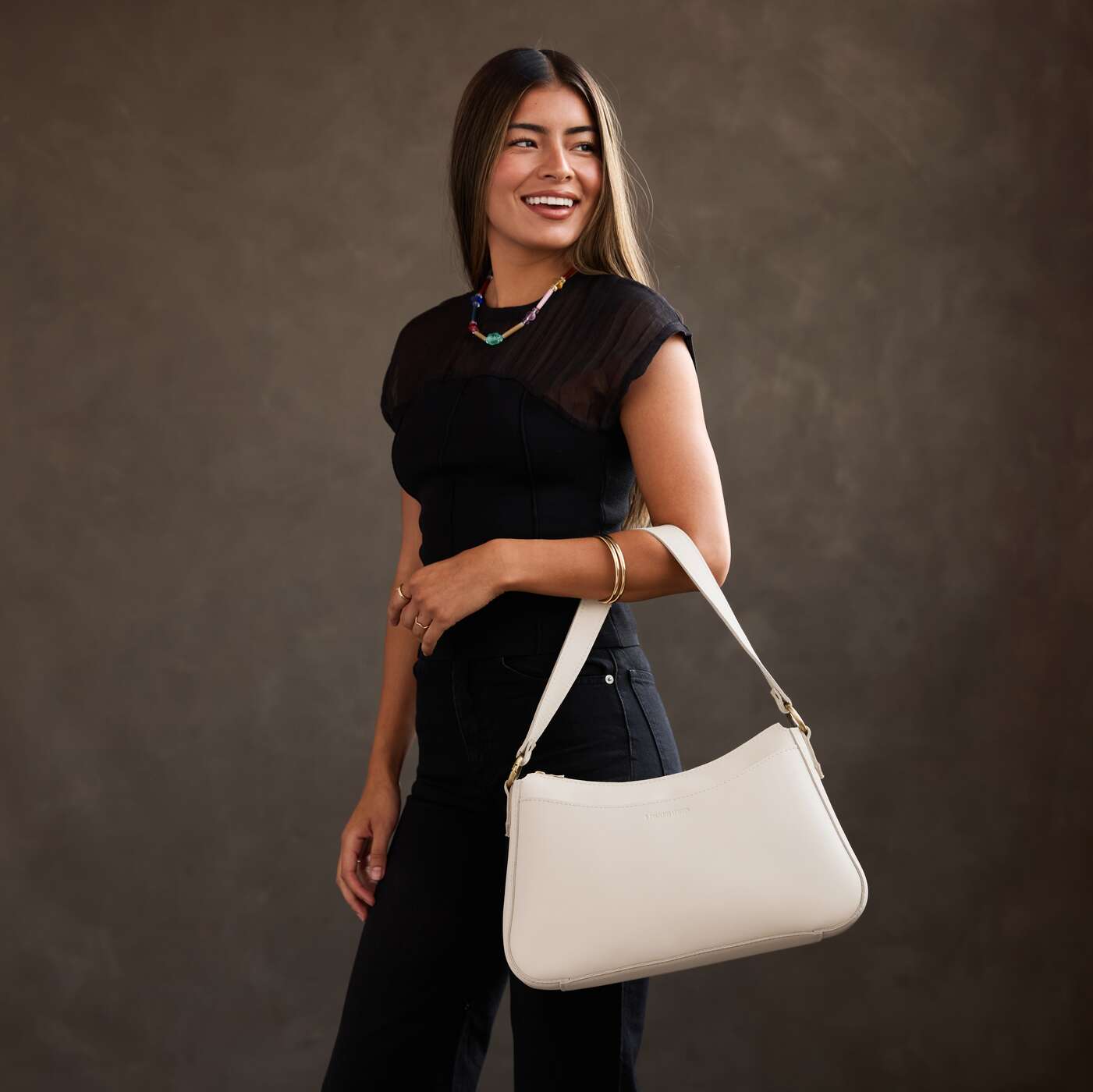 Bone*Large | Model holding a bean shaped shoulder bag with a zipper closure