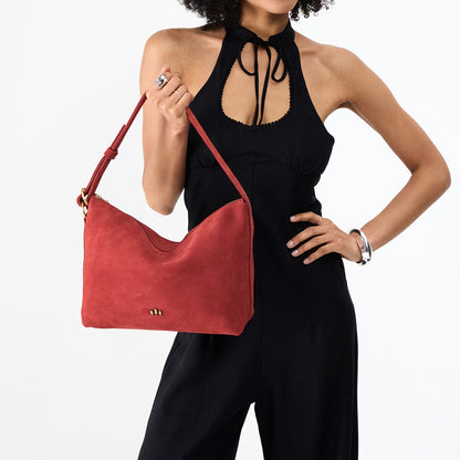 Cinnabar*Large | Model holding a Slouchy Shoulder Bag that has a zipper opening and three metal tree emblems
