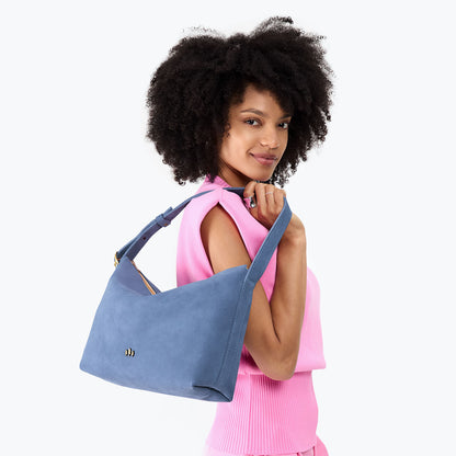 Denim*Large | Model holding a Slouchy Shoulder Bag that has a zipper opening and three metal tree emblems