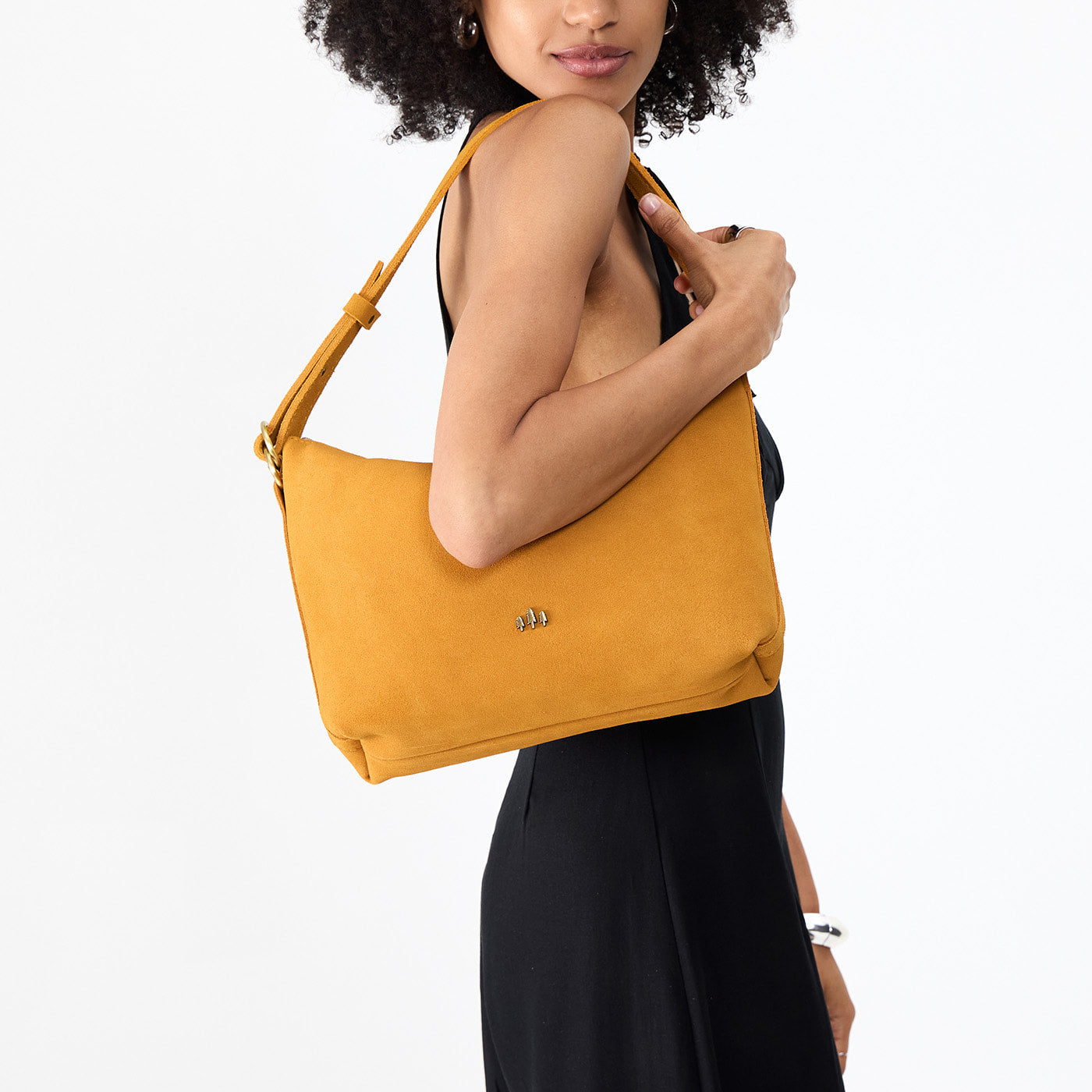 Dijon*Large | Model holding a Slouchy Shoulder Bag that has a zipper opening and three metal tree emblems