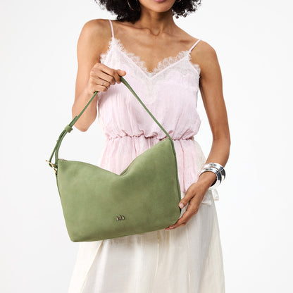 Laurel*Large | Model holding a Slouchy Shoulder Bag that has a zipper opening and three metal tree emblems