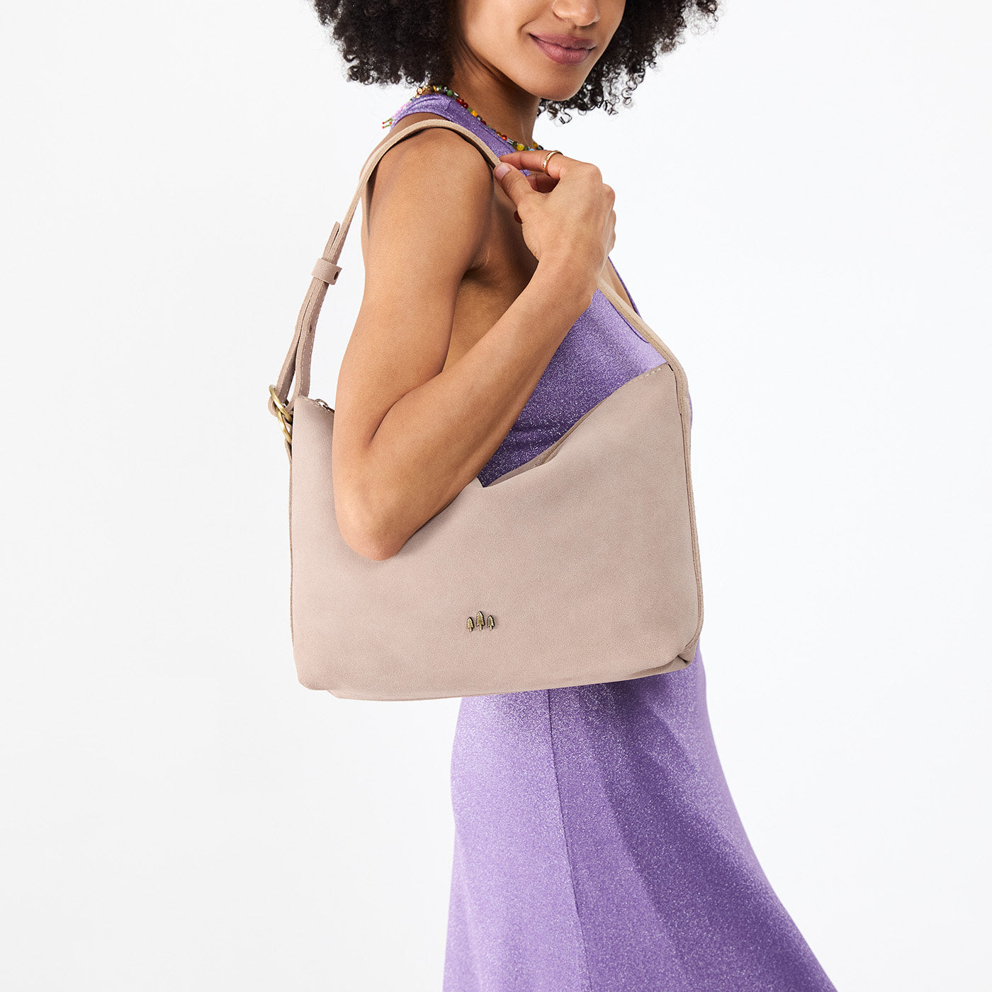 Taupe*Large | Model holding a Slouchy Shoulder Bag that has a zipper opening and three metal tree emblems