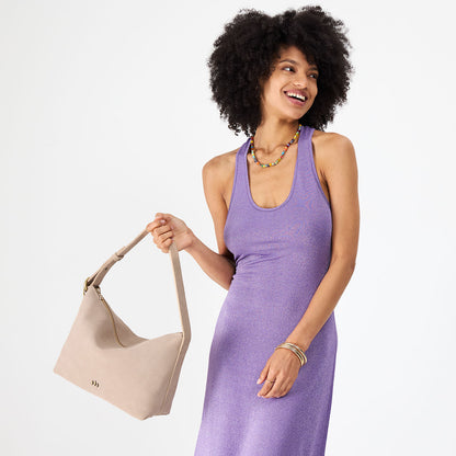 Taupe*Large | Model holding a Slouchy Shoulder Bag that has a zipper opening and three metal tree emblems
