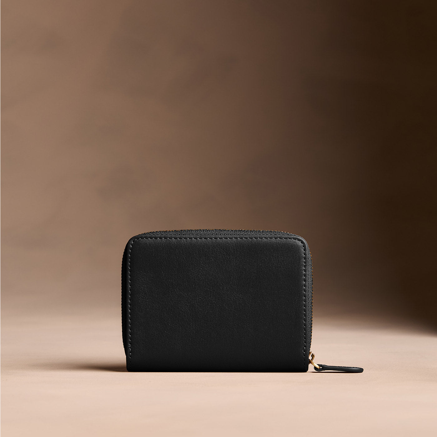 Onyx | Wallet with card and storage pockets on a light brown background - back view