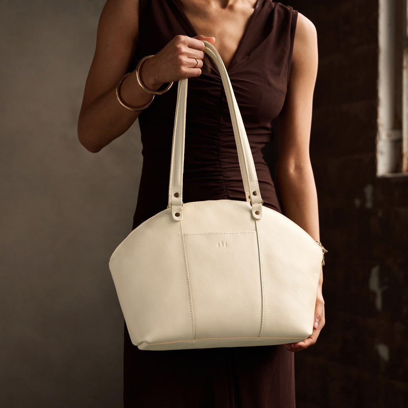 Pebbled Bone*Large | Model holding a half circle crossbody bag with handles and removable crossbody strap