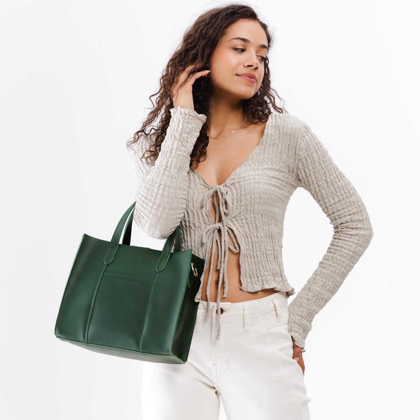Aruba | Model holding structured mid-size tote bag with overlapping panels and crossbody strap