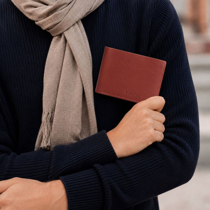 Marrone | A person wearing a sweater holding a bifold wallet