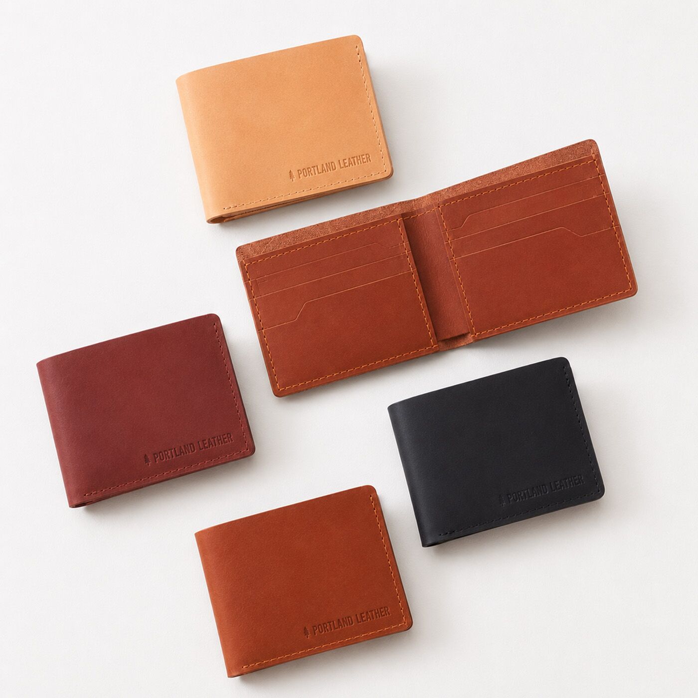 Nero | Five leather bifold wallets arranged on a clean white background. One wallet is open, showing the interior card slots, while the others are closed.