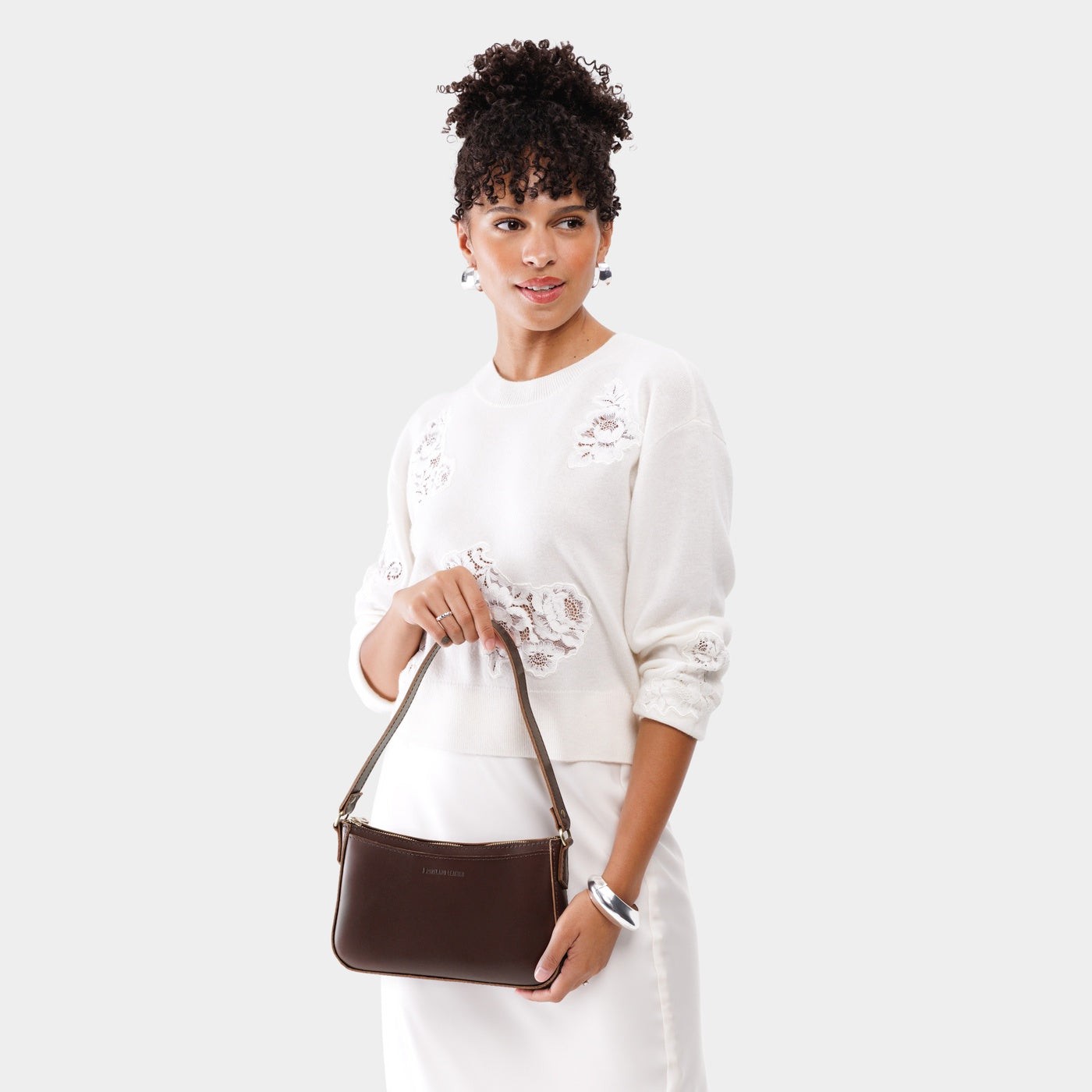 Chocolate Brown*Small | Model holding petite bean shaped shoulder bag with a zipper closure