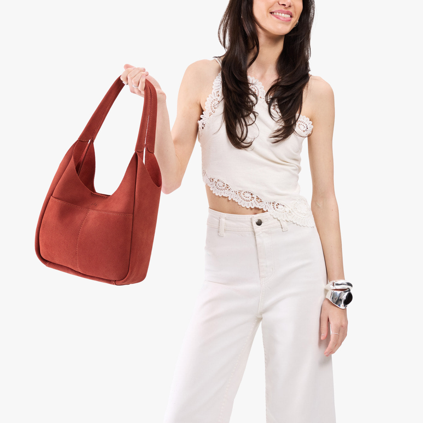 Cinnabar*Large | A model holding a u-shaped, flat-bottomed leather shoulder bag with two outside pockets