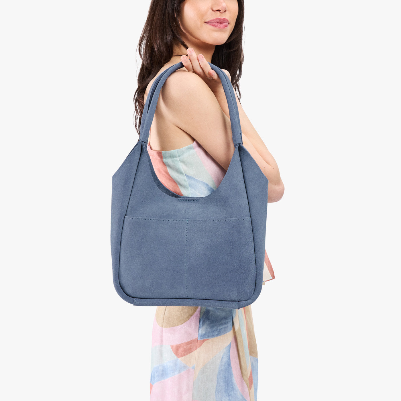 Denim*Large | A model holding a u-shaped, flat-bottomed leather shoulder bag with two outside pockets