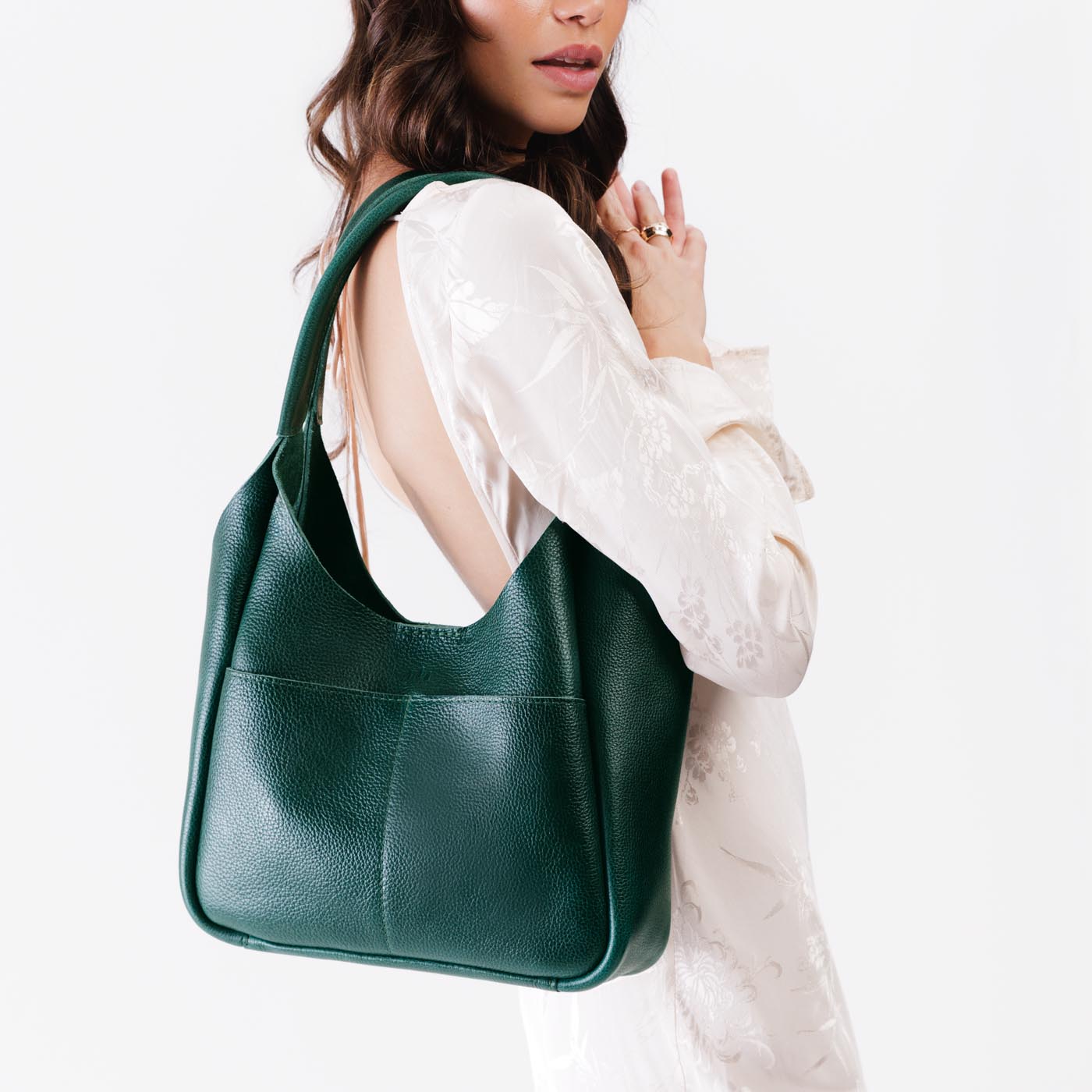 Forest Green*Large | A model holding a u-shaped, flat-bottomed leather shoulder bag with two outside pockets