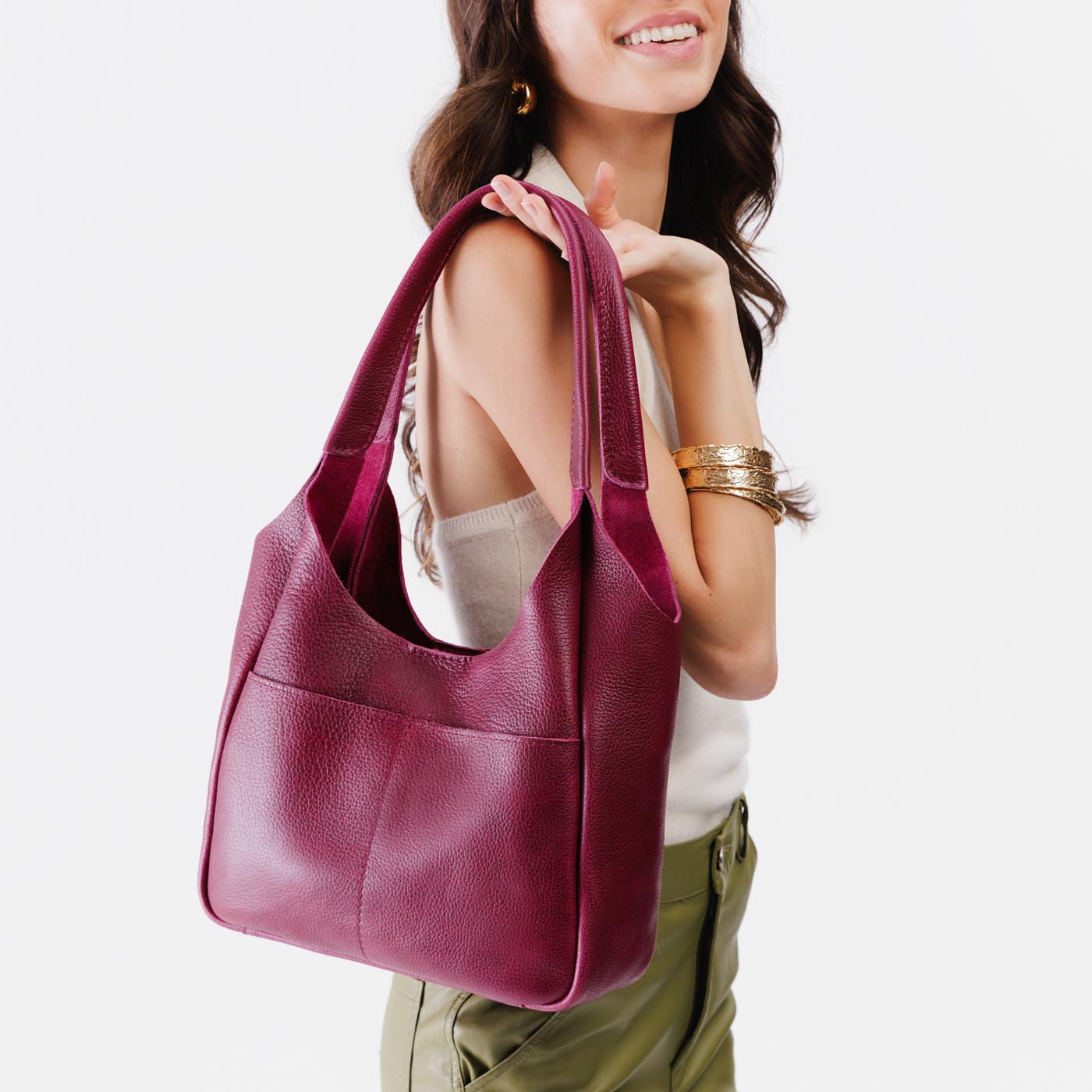 Orchid*Large | A model holding a u-shaped, flat-bottomed leather shoulder bag with two outside pockets