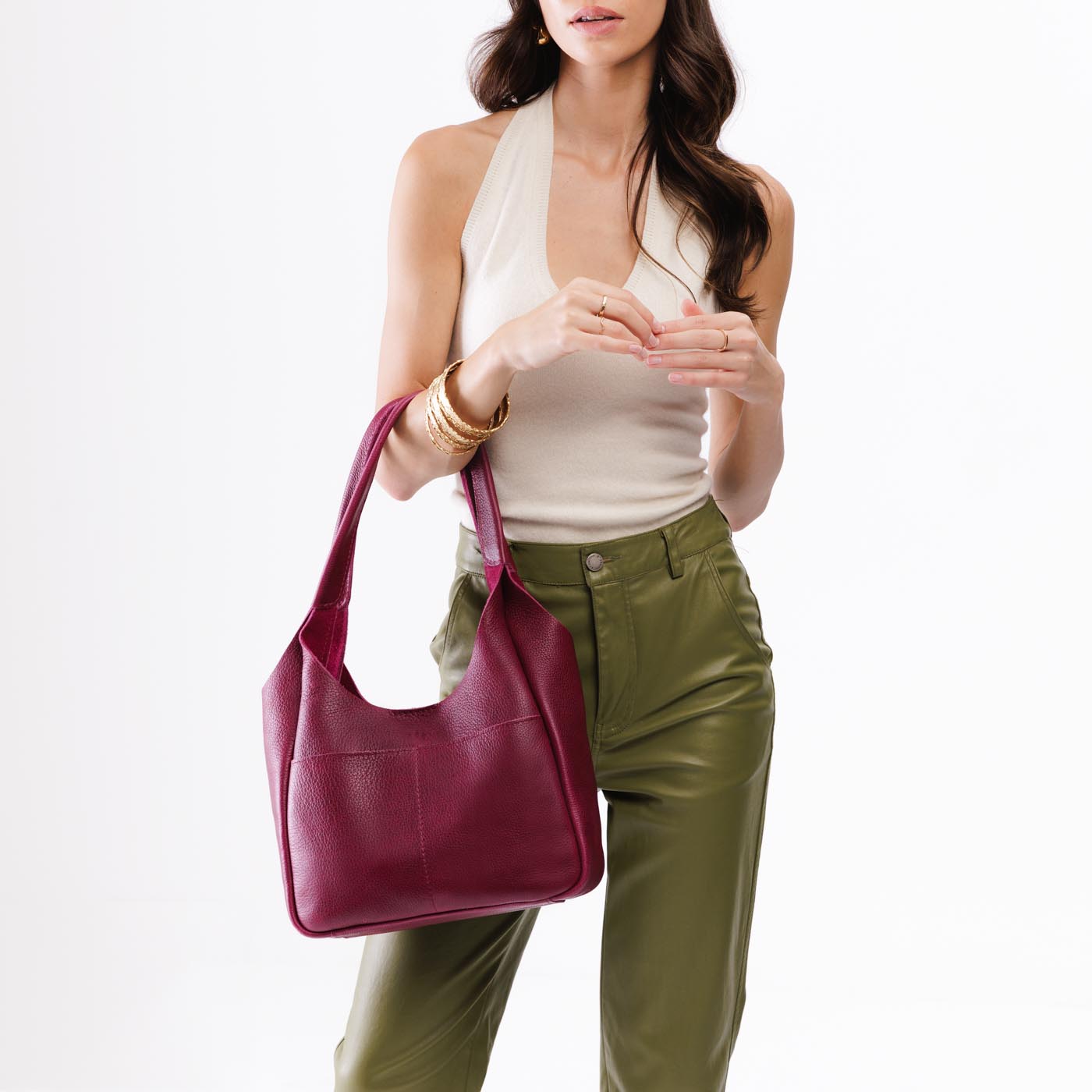 Orchid*Large | A model holding a u-shaped, flat-bottomed leather shoulder bag with two outside pockets