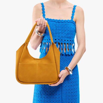 Dijon*Medium | A model holding a u-shaped, flat-bottomed leather shoulder bag with two outside pockets