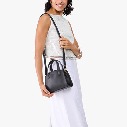 Black*Mini | Model carrying small leather tote bag with handles, adjustable crossbody strap, and one back pocket