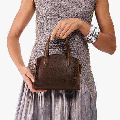 Coldbrew*Mini | Model holding small leather tote bag with handles, adjustable crossbody strap, and one back pocket