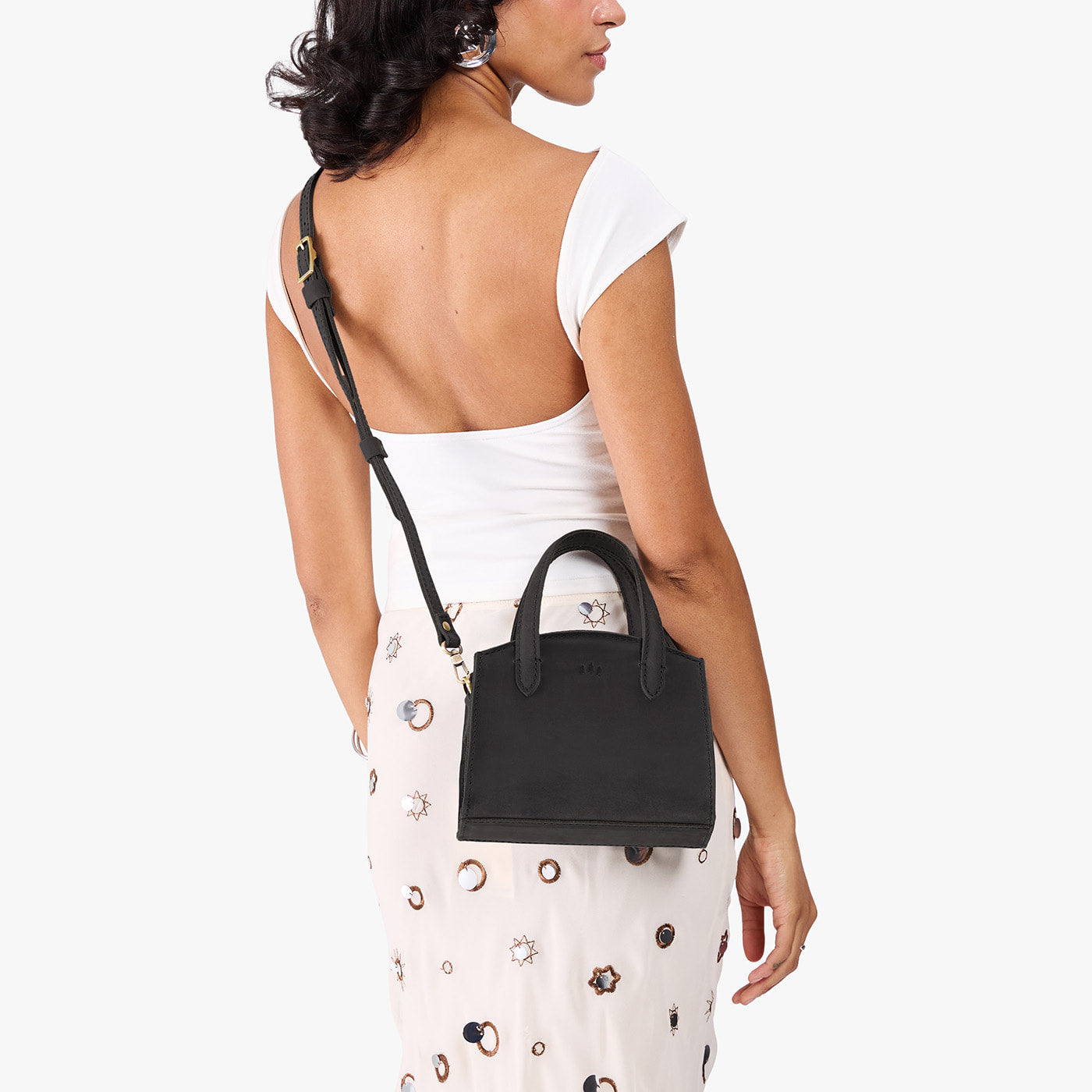 Full Moon*Mini | Model carrying small leather tote bag with handles, adjustable crossbody strap, and one back pocket