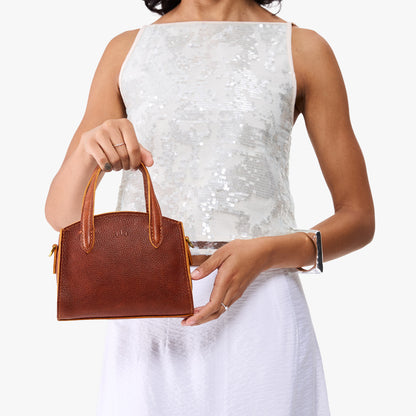 Nutmeg*Mini | Model carrying small leather tote bag with handles, adjustable crossbody strap, and one back pocket