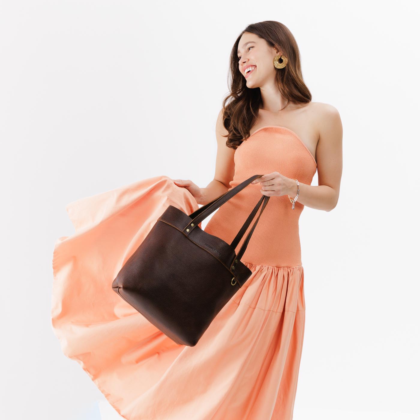 Coldbrew*Medium*Classic | Model holding leather tote bag with riveted straps and exterior key loop