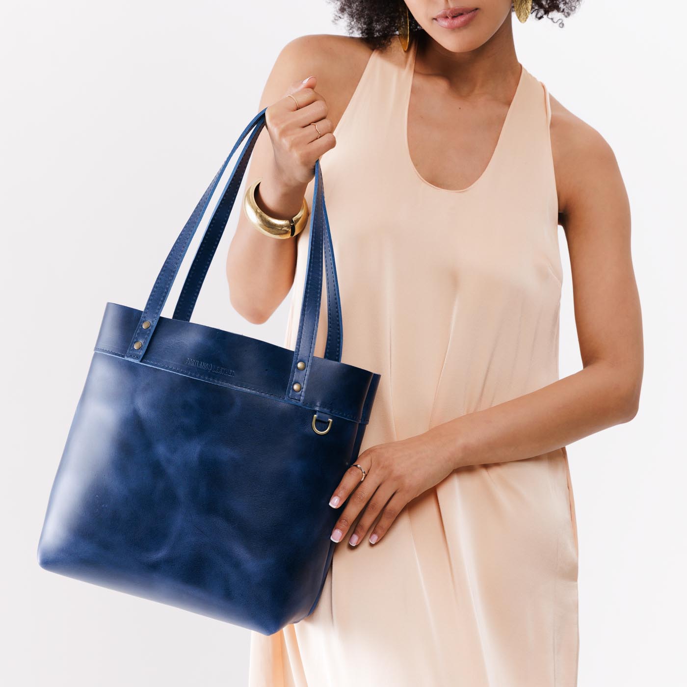Cowboy Blue*Medium*Classic | Model holding leather tote bag with riveted straps and exterior key loop
