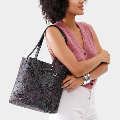 Masquerade*Medium*Classic | Model holding a leather tote bag with riveted straps and exterior key loop