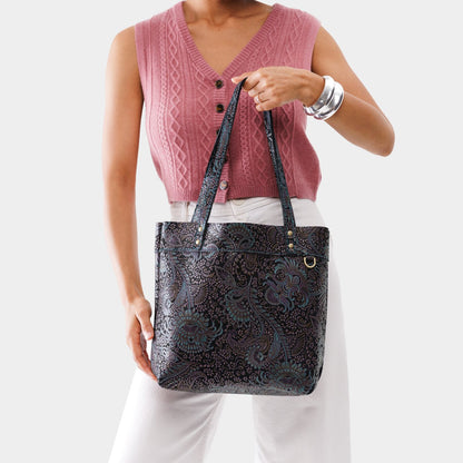 Masquerade*Medium*Classic | Model holding a leather tote bag with riveted straps and exterior key loop