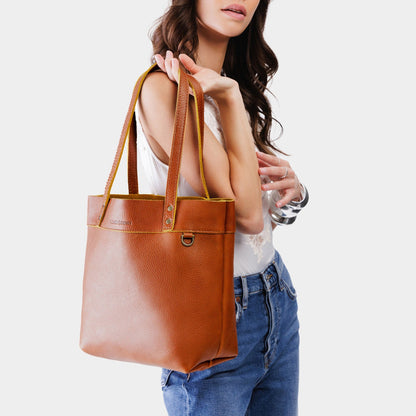 Sienna*Medium*Classic | Model holding a leather tote bag with riveted straps and exterior key loop