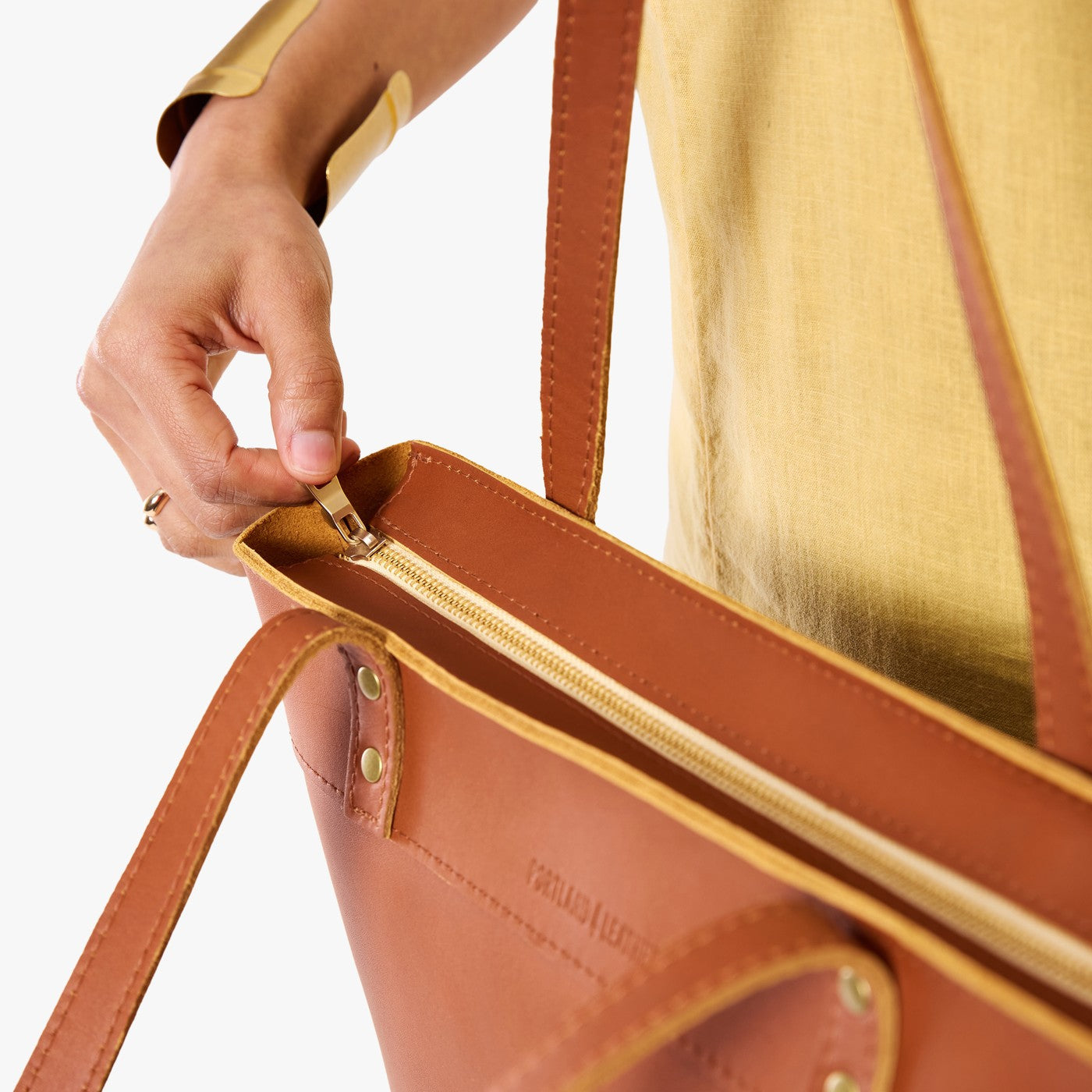 Honey*Medium*Zipper | Model wearing leather tote bag with riveted straps and exterior key loop