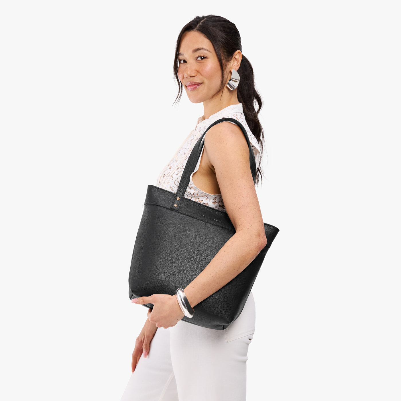 Pebbled--black*Medium*Zipper | Model wearing leather tote bag with riveted straps and exterior key loop