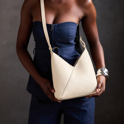 Pebbled Bone*Small | Model holding petite shoulder bag with adjustable strap and magnetic snap closure