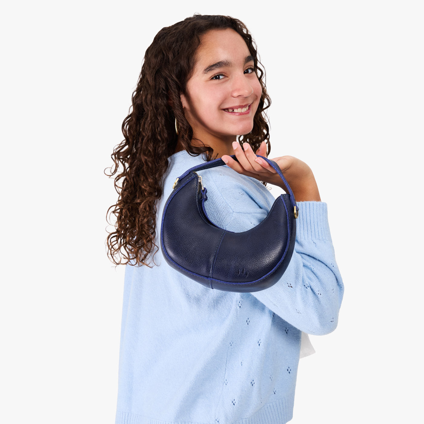Cobalt | Model with a crescent shaped shoulder bag with zipper closure and gold accents