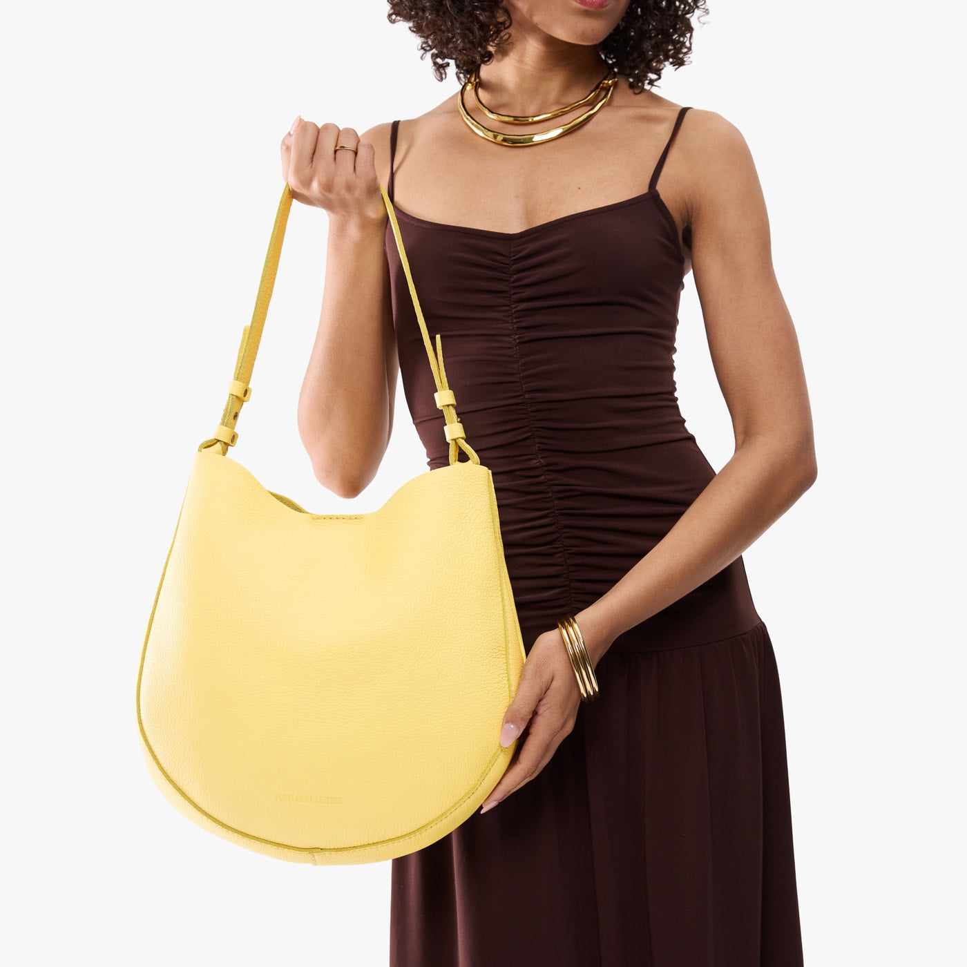Butter Bliss*Large | Model holding round leather purse with adjustable shoulder strap