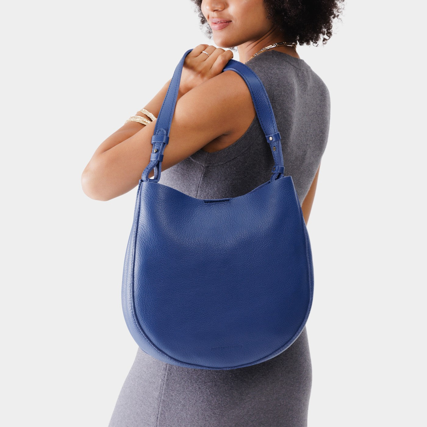 Molino Blue*Large | Woman wearing rounded shoulder bag with adjustable strap on a white background
