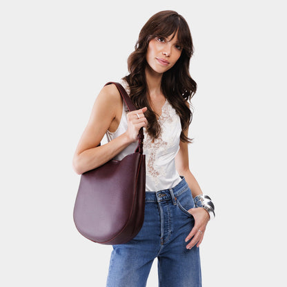 Plum*Large | Woman wearing rounded shoulder bag with adjustable strap on a white background