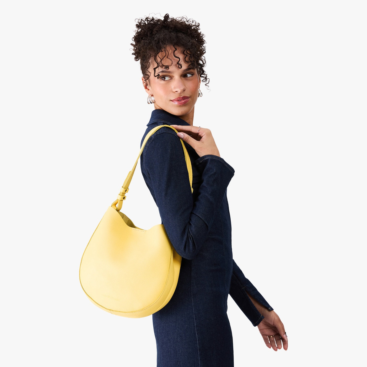 Butter Bliss*Medium | Model carrying round leather purse with adjustable shoulder strap