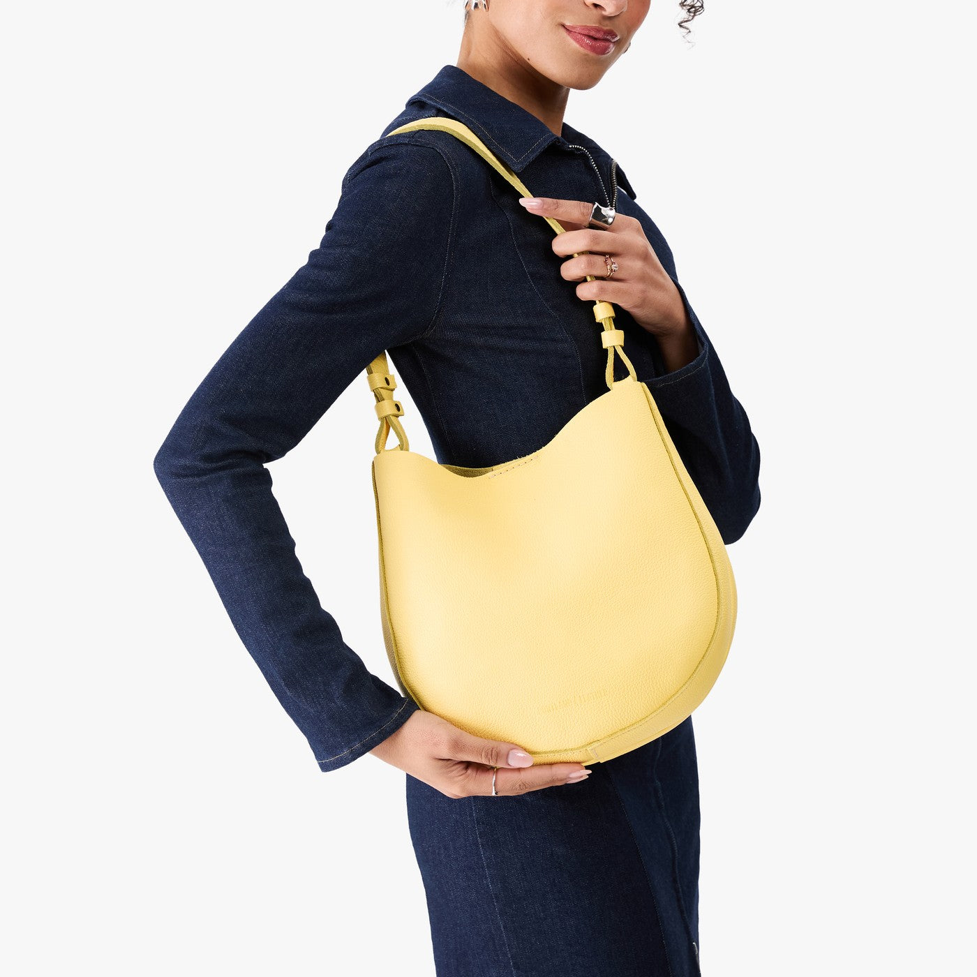 Butter Bliss*Medium | Model carrying round leather purse with adjustable shoulder strap