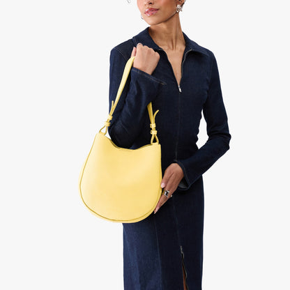 Butter Bliss*Medium | Model carrying round leather purse with adjustable shoulder strap