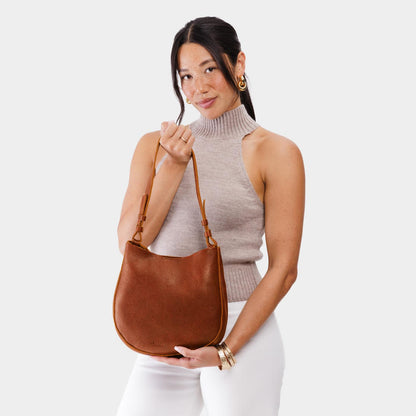 Nutmeg*Medium | Woman wearing rounded shoulder bag with adjustable strap on a white background