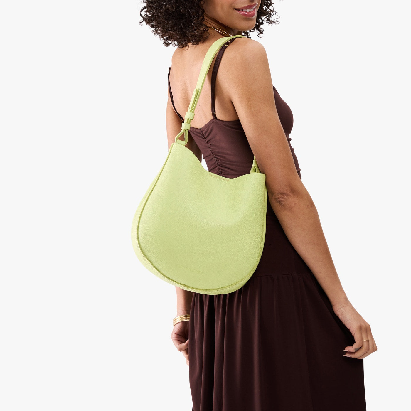 Shadow Lime*Medium | Model carrying round leather purse with adjustable shoulder strap
