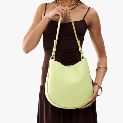 Shadow Lime*Medium | Model holding round leather purse with adjustable shoulder strap