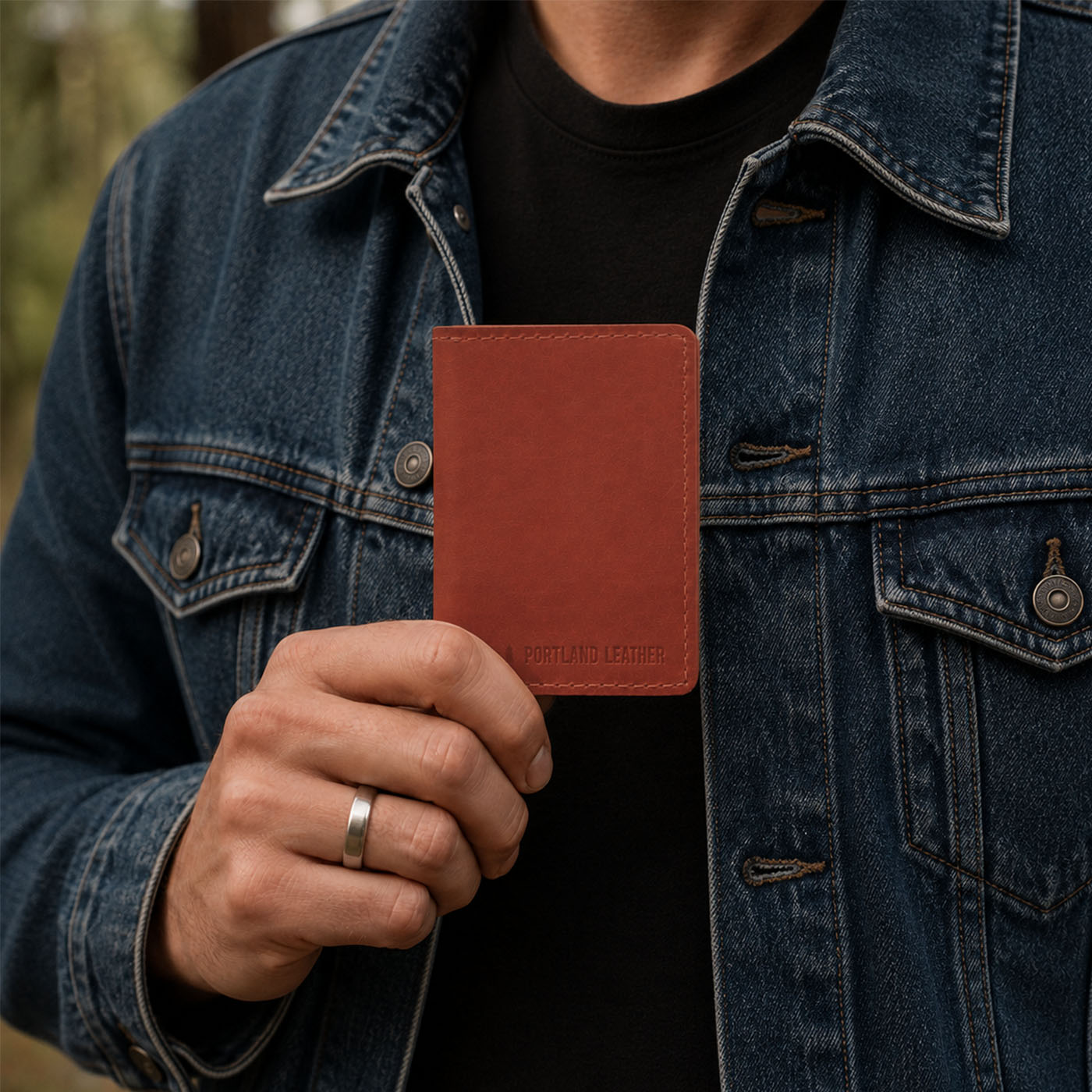 Marrone | A close-up lifestyle shot of a model holding a leather card holder