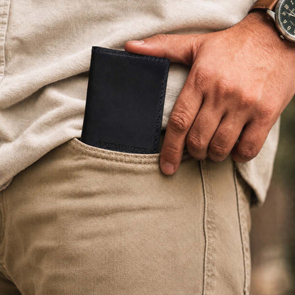 Nero | A close up of a model sliding a leather card holder into their pants pocket