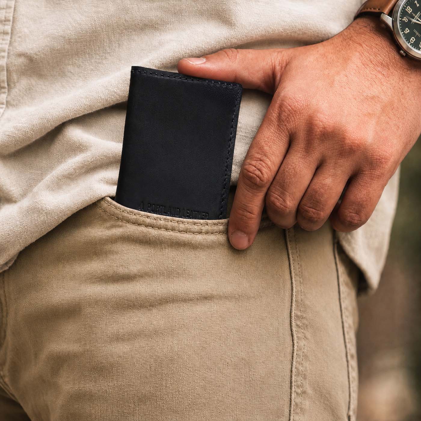 Nero | A close up of a model sliding a leather card holder into their pants pocket