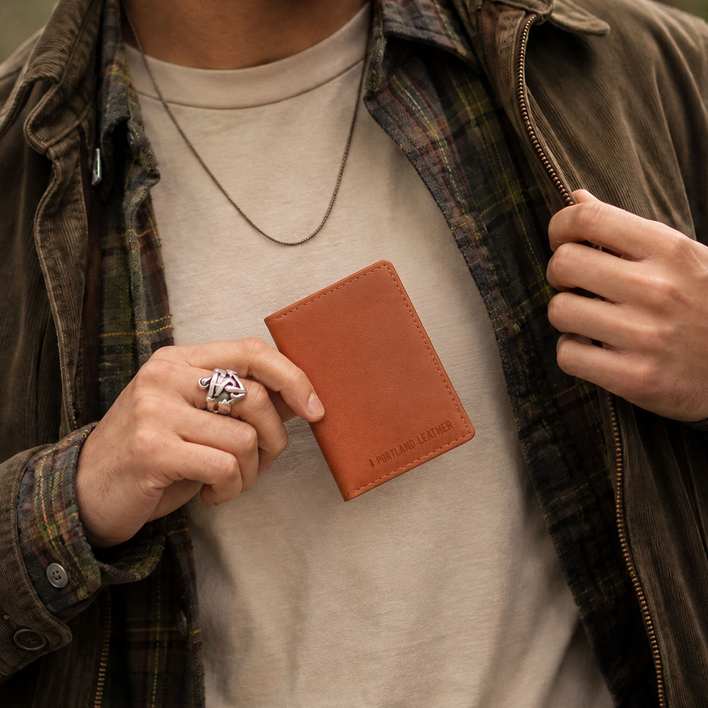 Toscano | A close-up lifestyle shot of a model holding a leather card holder